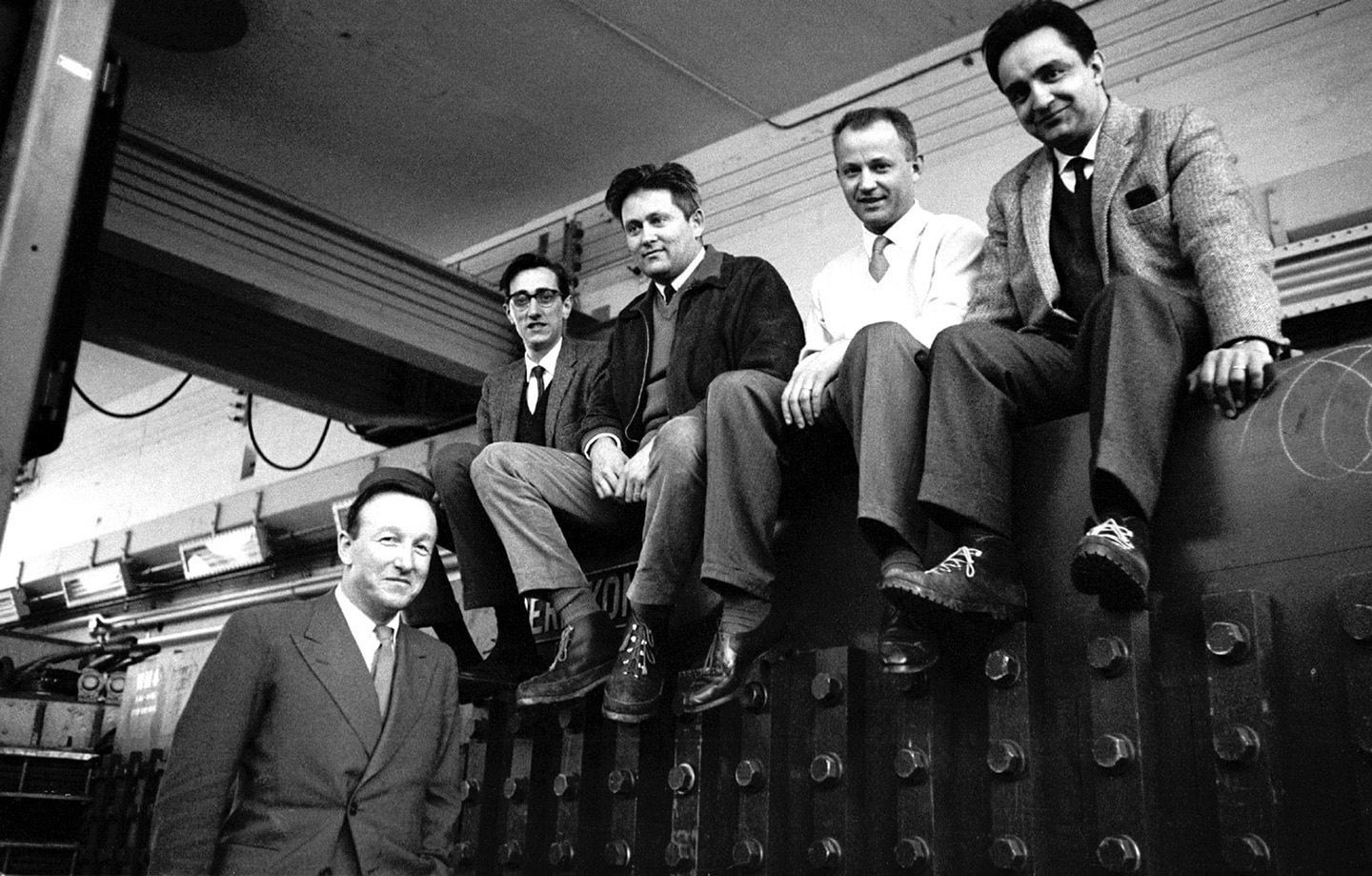 Man standing next to four men sitting on a magnet