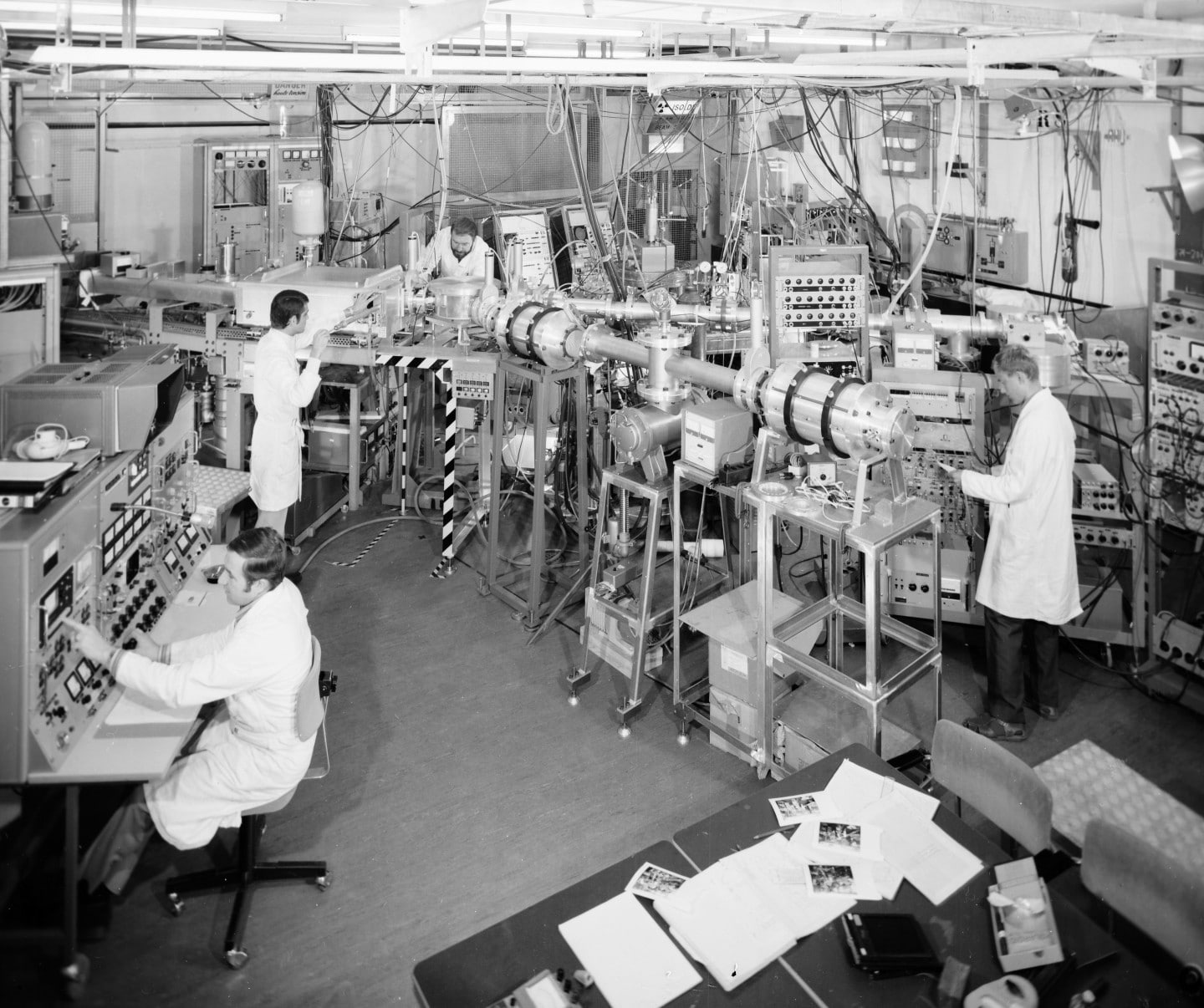 People in white lab coats surrounded by equipment in an experimental hall