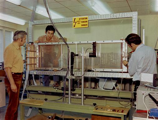 Three men next to a detector