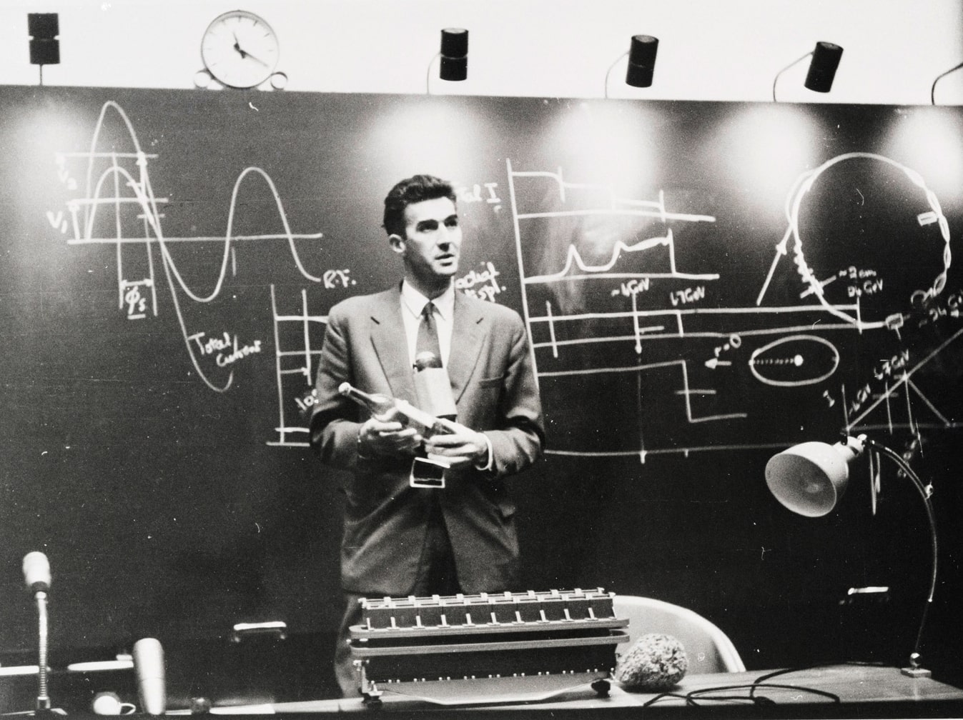 Man holding bottle in front of blackboard of equations